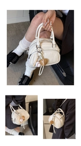 Detail of cream white pillow bag with baseball charms and textured leather finish