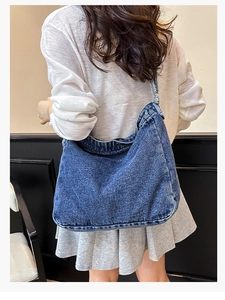 Dettaglio della borsa hobo in denim blu con trama lavata e bordi sfrangiati