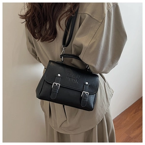 Close-up of black PU leather bag with PAN TOR embossing and silver metal buckle