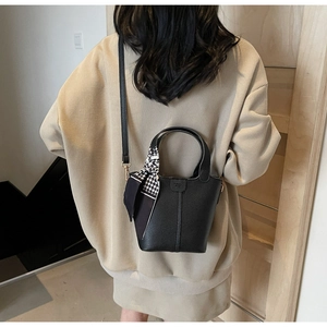 Detail of black lychee grain leather bucket bag with houndstooth ribbon and handle