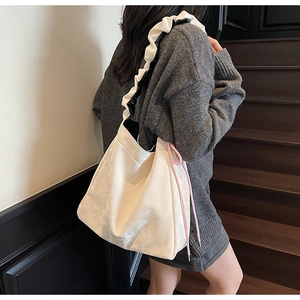 Detail of off-white tote bag with ruffled shoulder strap and pink drawstring accents