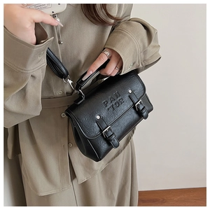 Detail of black pebbled leather crossbody bag with PAN TOR embossed lettering and buckles