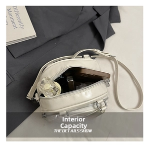 Detail showing internal capacity of the cream pillow bag with cosmetics and phone