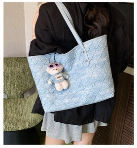 Close-up of light blue tote bag with unique wavy 3D texture and cute bear charm detail