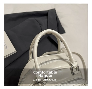 Detailed view of the off-white leather handbag showing dual handles and silver metal hardware
