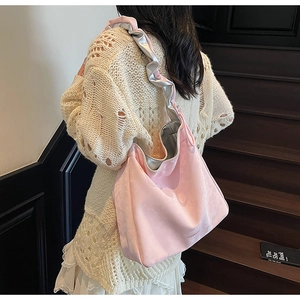 Sac fourre-tout rose plissé avec bandoulière à volants porté par un mannequin en ville