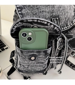 Bolsillo frontal de mochila vaquera con cierre de presión mostrando espacio para el móvil