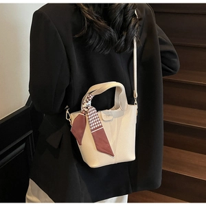 Detail of beige bucket bag with lychee leather texture and chic houndstooth silk scarf handle