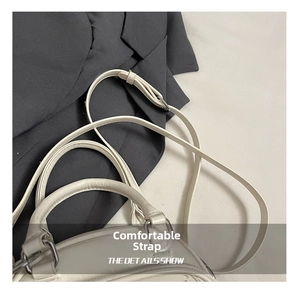 Detail of minimalist ivory handbag showing comfortable handle and adjustable shoulder strap