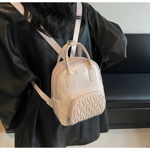 Detail view of cream white backpack featuring quilted texture and mesh side panels
