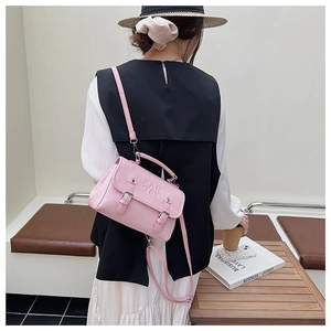 Close-up of a pink mini square crossbody bag showing leather texture and buckled design