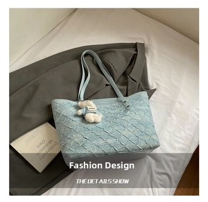 Detail of light blue tote bag featuring wavy pleated texture and a cute white teddy bear charm