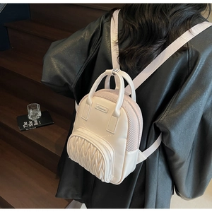 Chic cream mini backpack with wave quilting shown on model in urban lifestyle scene