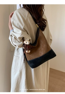 Borsa hobo retrò marrone e nera indossata da una modella con ciondolo a orsetto