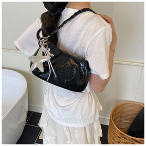 Détail du sac en cuir huilé brillant avec bandoulière tressée et pendentif étoile argentée