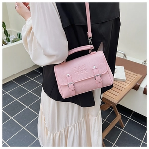Detailed shot of pink faux leather crossbody bag with PAN TOR embossed texture and buckles