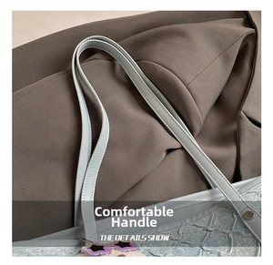 Detail of light blue tote bag handle with refined stitching and textured fabric