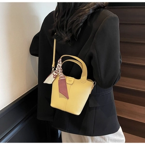 Detail of yellow leather bucket bag with decorative silk scarf and fashion logo