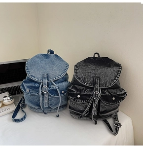 Primer plano detallado de mochilas denim retro en azul y gris con textura lavada y bolsillos