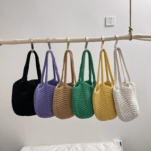 Sacs cabas au crochet faits main en six couleurs suspendus sur un rail en bois épuré