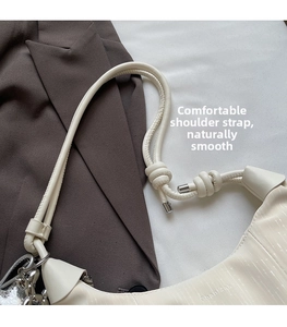 Detail of off-white crossbody bag with thick knot strap design on a brown suit jacket