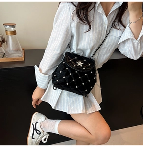 Detail of black quilted patent leather bag with rhinestone stars and chain strap