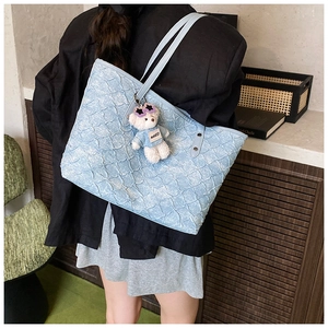 Detail of light blue tote bag with bubble texture fabric and cute teddy bear pendant