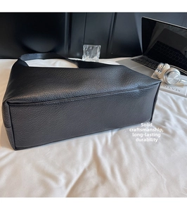 Dettaglio della base in pelle nera con motivo litchi e cuciture per una grande borsa tote