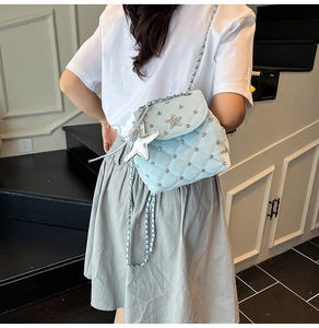 Detail of light blue quilted crossbody bag with star studs and large star pendant