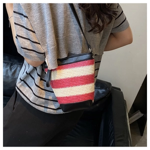 Detail of red and white striped woven bucket bag with black leather base and shoulder strap