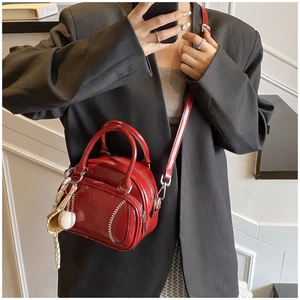 Detail of red patent leather baseball handbag with white stitching and glove charm