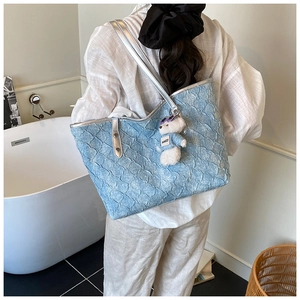 Detail of light blue wrinkled tote bag with silver metallic handles and a teddy bear charm