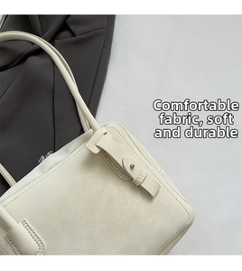 Close-up of minimalist cream tote bag showing soft pebbled texture and fine stitching