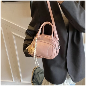 Detail of pink patent leather handbag with embossed logo and cute cookie charm accessory