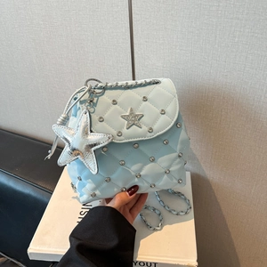 Detail der hellblauen Stepptasche mit silbernen Sternanhängern und Strasssteinen