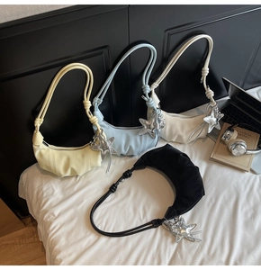 Detail of four colorful pleated half-moon bags with silver star charms on a white bed