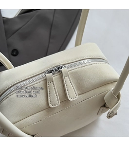 Detail of smooth silver double zippers on creamy white lychee grain leather tote bag