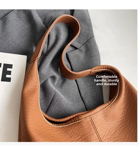 Nahaufnahme der braunen Schultertasche mit Litschimuster, breitem Riemen und Nähten