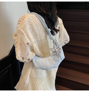 Light blue crescent shoulder bag with knot detail and star charm on knit sweater