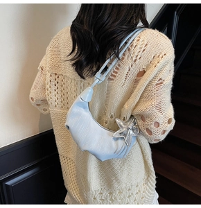 Detail of light blue crescent bag with silver starfish charm on mesh knit outfit