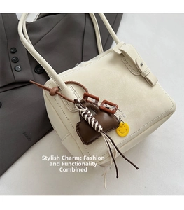 Detail of cream minimalist tote bag with trendy mini pouch and yellow smiley face charms