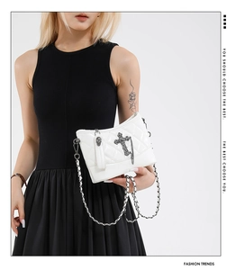 Detail of white quilted bucket bag featuring punk gothic cross and skull charms with chain