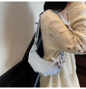 Detail of light blue crescent bag with ripple texture and silver star pendant charm