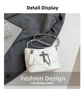 Close-up of white quilted leather bucket bag with silver cross and skull chain charms