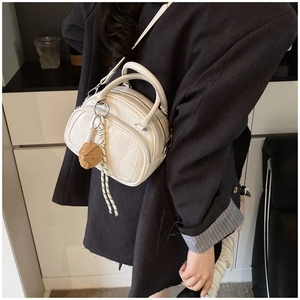 Detail of white glossy mini pillow bag with biscuit charm and woven rope strap