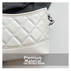 Macro detail of white quilted faux leather texture and metallic chain buckle on the bag