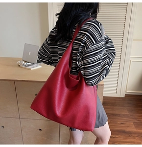 Dettaglio della texture in pelle martellata rossa e della capienza della borsa a spalla