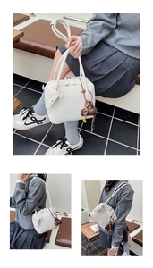 Detail of white minimalist leather tote bag with brown heart charm and sleek zipper closure