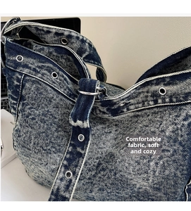 Detail of heavy denim tote bag with vintage wash, eyelet accents and wide shoulder strap