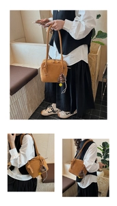 Detailed view of a brown minimalist leather tote bag with decorative charms and slim straps